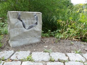 Einkaufstasche aus Beton im Beet